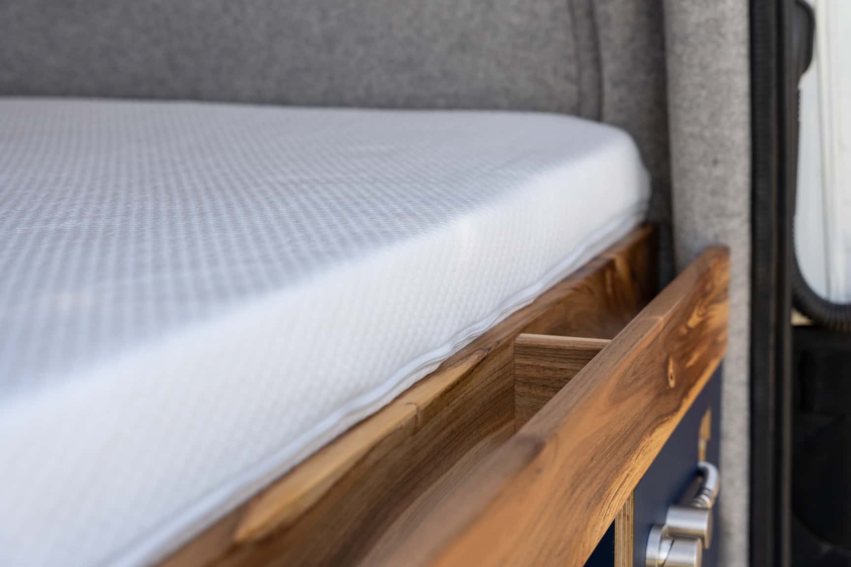 Walnut shelf behind the transverse bed in the Sprinter L3H2 conversion